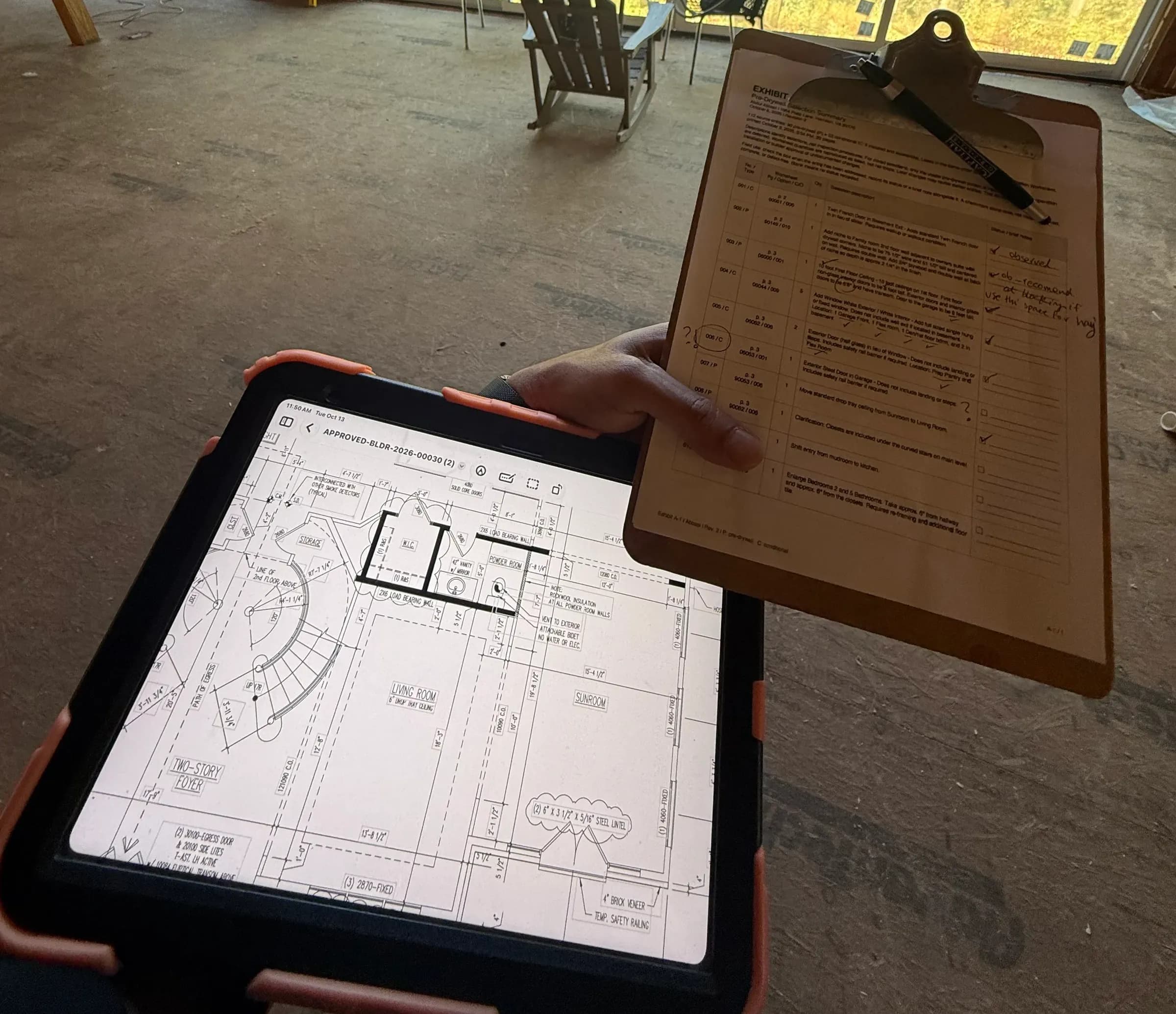 Inspector holding a construction checklist beside a tablet displaying floor plans inside an unfinished home.